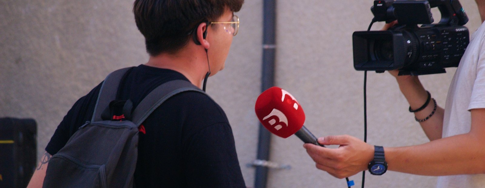 A reporter interviewing with a microphone and camera
